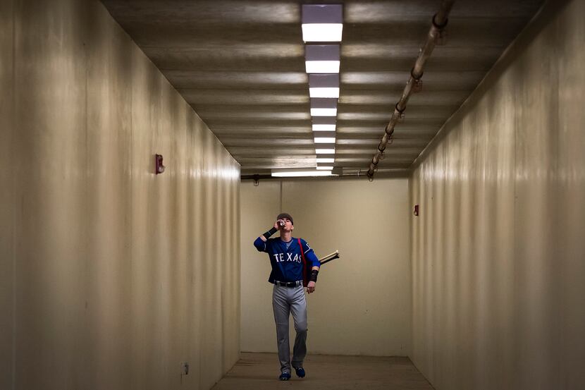 Texas Rangers outfielder Carlos Tocci downs an energy drink as he walks from the clubhouse...