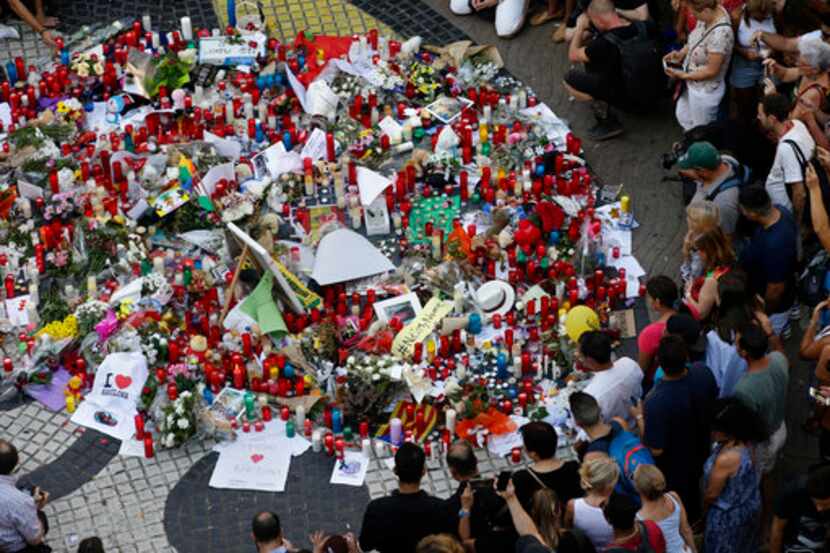 Gente se aglomera en un altar con flores, mensajes y velas en homenaje a las víctimas de un...