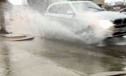 Morning commuters plow through pouring rain on North Henderson Avenue on the east side of...