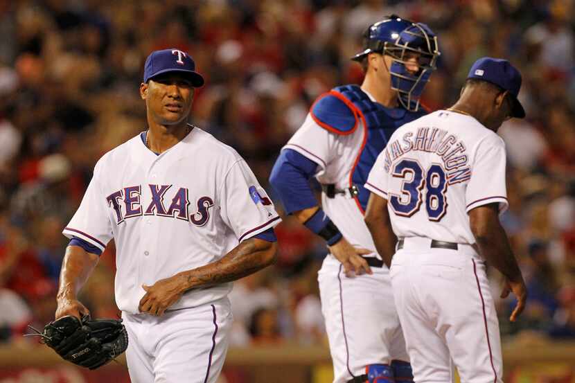 Rangers starter Alexi Ogando (left) is pulled in the seventh inning by manager Ron...