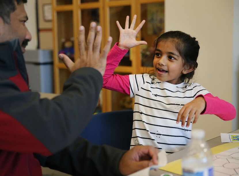 
Anoshka Mody, 5, gives a high-five to her father, Chandan Mody while they work on a puzzle...