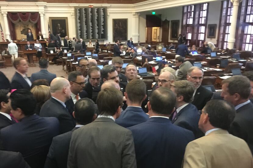 House members huddle at the back of the chamber late Thursday after Rep. Jonathan Stickland...