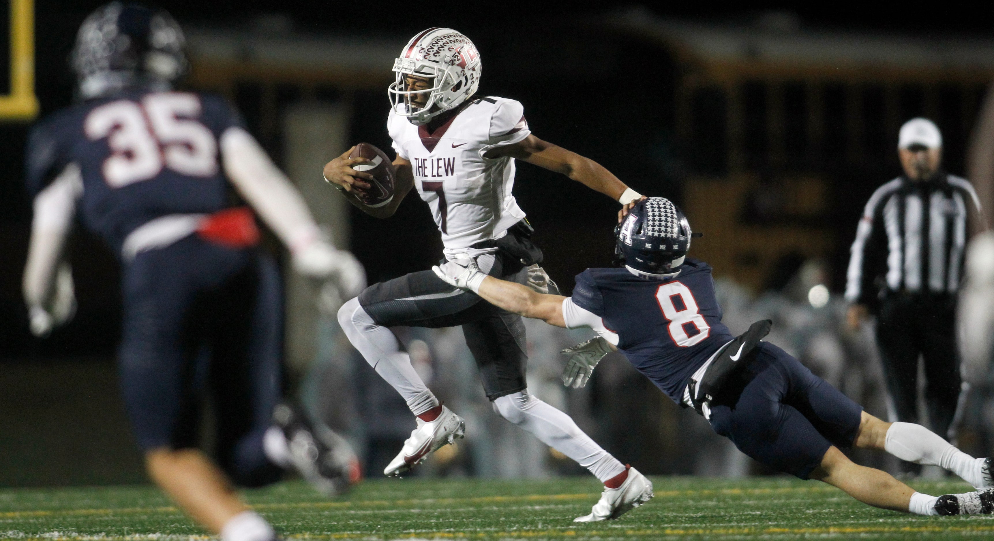 Lewisville quarterback Ethan Terrell (7), center, works to elude the attempted tackle by...