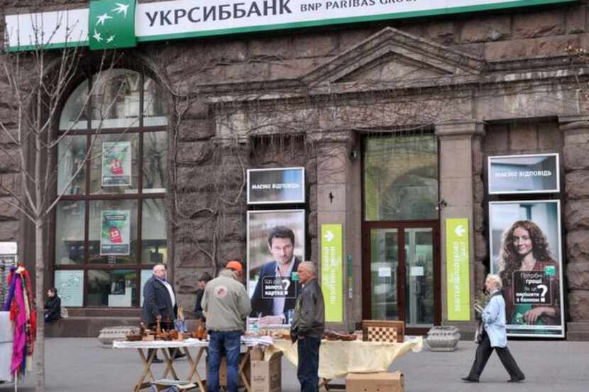 
People walk in front of a branch of UkrSibBank in Kiev Tuesday. French bank BNP Paribas...