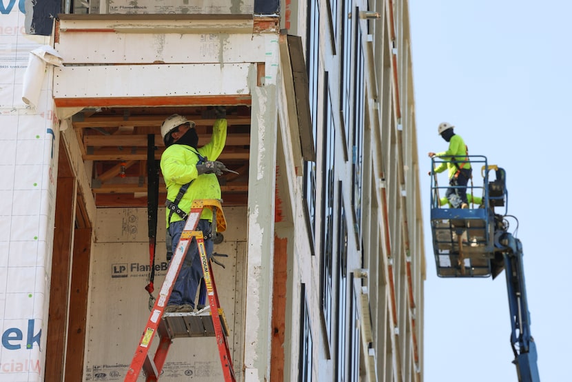 Construction workers work at an under construction apartment going up in Deep Ellum, on...