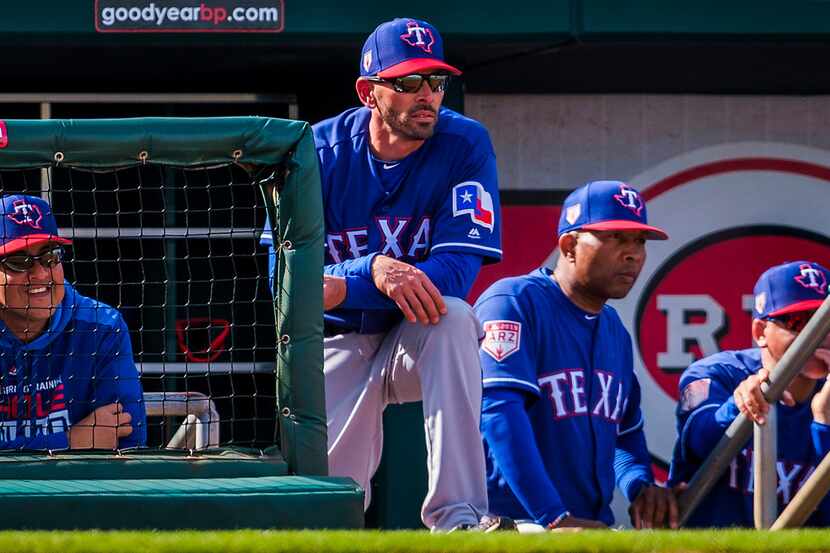 Texas Rangers manager Chris Woodward (center) watches from the top step of the dugout with...