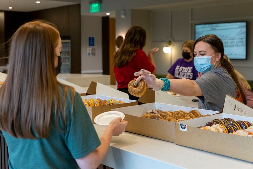 Merit Energy human resources administrator Chloe Geoghegan hands a doughnut to senior...