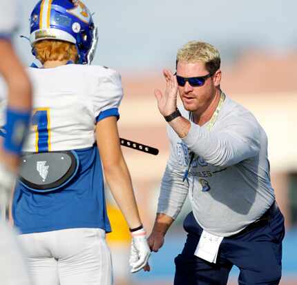 Brock High School head football coach Billy Mathis demonstrates technique to a player during...