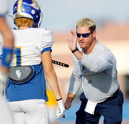 Brock High School head football coach Billy Mathis demonstrates technique to a player during...