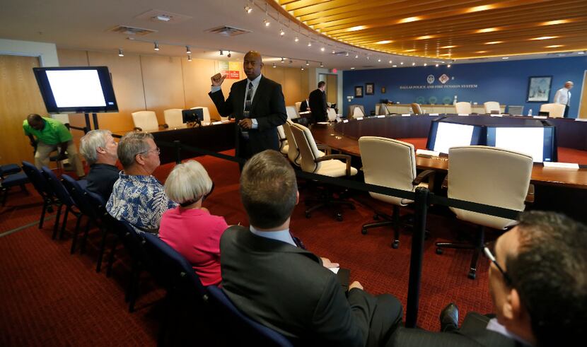 Chairman Sam Friar (standing in a suit) talked with people in the audience during a break at...