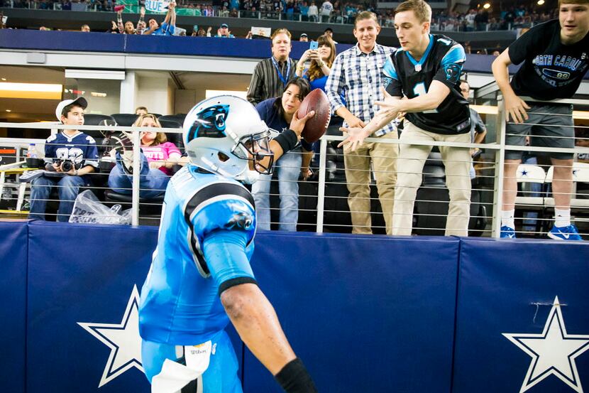Carolina Panthers quarterback Cam Newton hands the ball to a fan after scoring on a 4-yard...