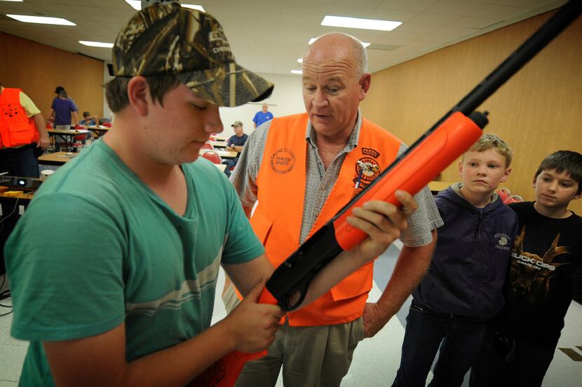 Brandon Yates, left, 16, of McPherson, Kan., holds a demonstration semi automatic shot gun...