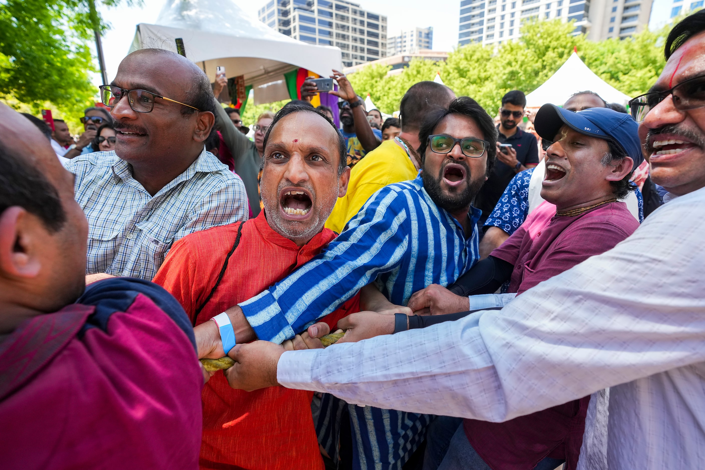 Men heave on ropes to pull Ratha Yatra parade chariot during the Festival of Joy on...