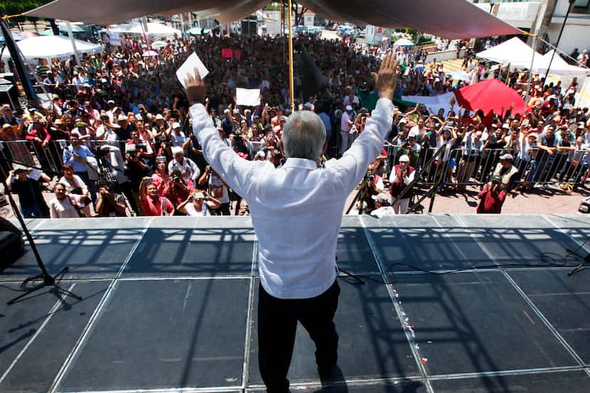 In this April, 2017 photo, presidential hopeful Andres Manuel Lopez Obrador raises his arms...