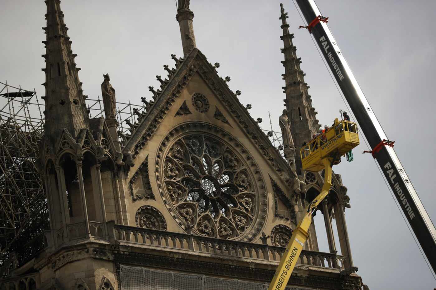 Technicians work in a crane next to Notre Dame cathedral in Paris April 22, 2019. 