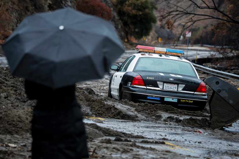 A backhoe works to free a Los Angeles Police Department police squad car stuck in the mud...