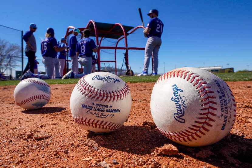 Baseballs rest on the warning track as Texas Rangers players, including Jared Walsh (21),...