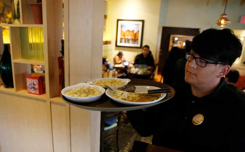 Salomon Guerra takes a tray of plates to customers at Olive Garden in Dallas, on Monday,...