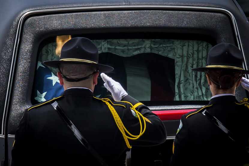 Law enforcement officers saluted the hearse carrying the casket of Dallas Police Officer...