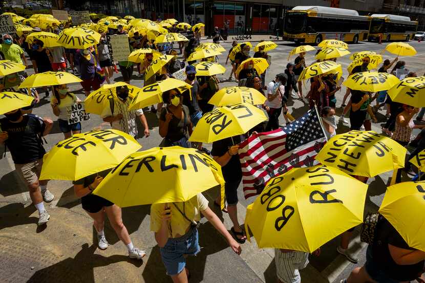 Demonstrators, many carrying umbrellas bearing the names of people who have been killed by...