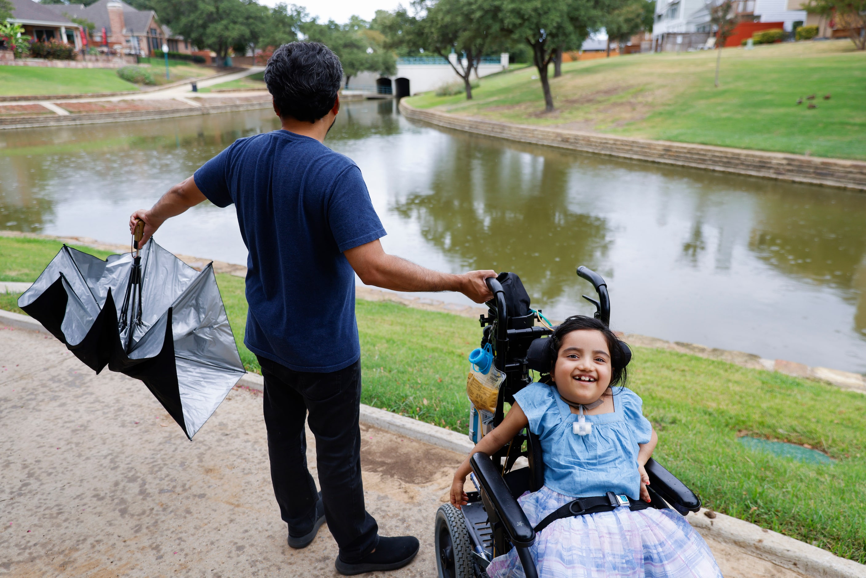 Kiran Ramachandran closes his umbrella during a stroll with his daughter Aadya Warrier on...