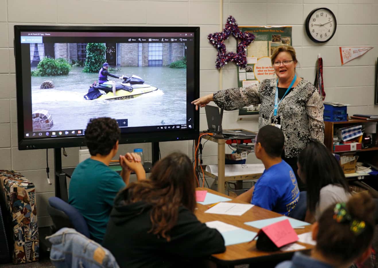 Eighth grade teacher Joan Brandt shows her class photos of the massive amount of water that...