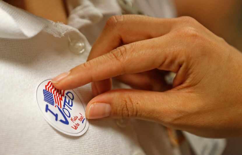 A third-grader receives a "I voted" sticker from a school staff in the mock election that...