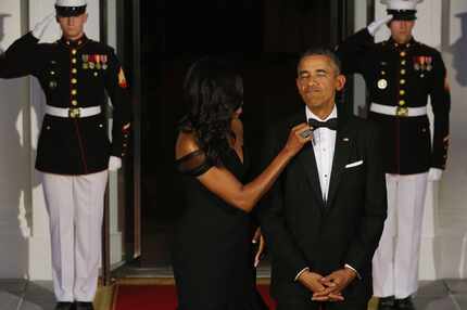  First Lady Michelle Obama straightens President Obama's tie while they await the arrival of...