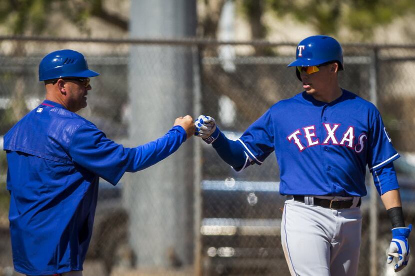 Texas Rangers infielder Drew Robinson gets a fist bump from third base coach Spike Jones...