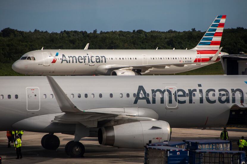 An American Airlines plane taxis away from another parked at the gates of Las Americas...