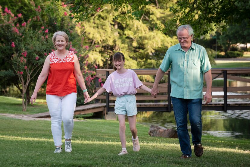 Claire Aldridge, left, Matt Burnside, and their 12-year-old daughter Lucy Burnside walk hand...