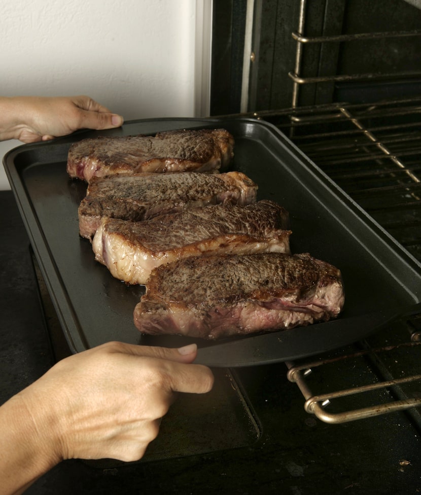 Finishing New York strip steaks in the oven.