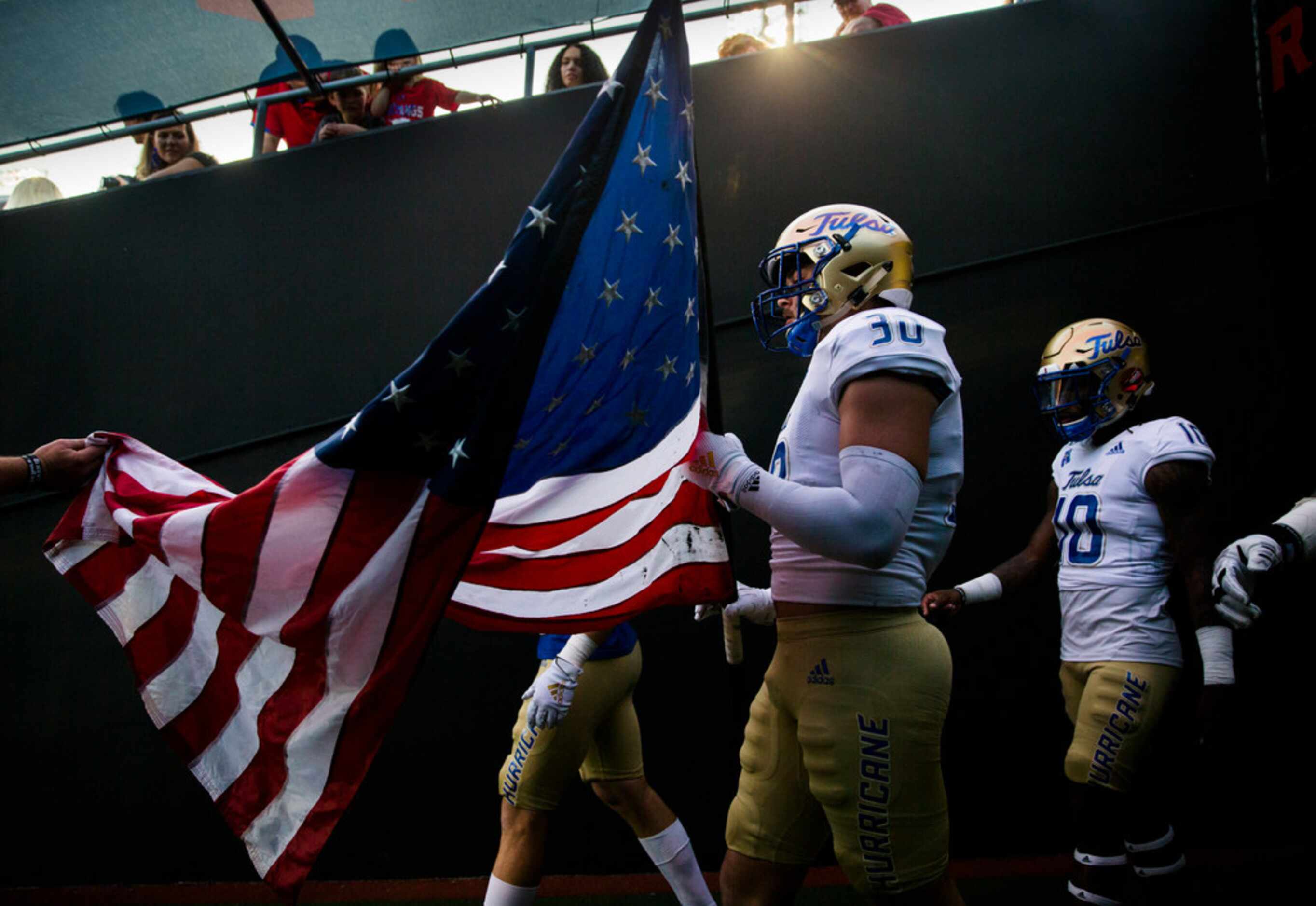 Tulsa Golden Hurricane linebacker Justin Wright (30) holds an American flag in the tunnel...