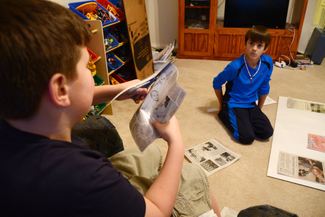 Jake Oxford, 12, (left) and his brother, Luke, 8, organize newspaper clippings about their...