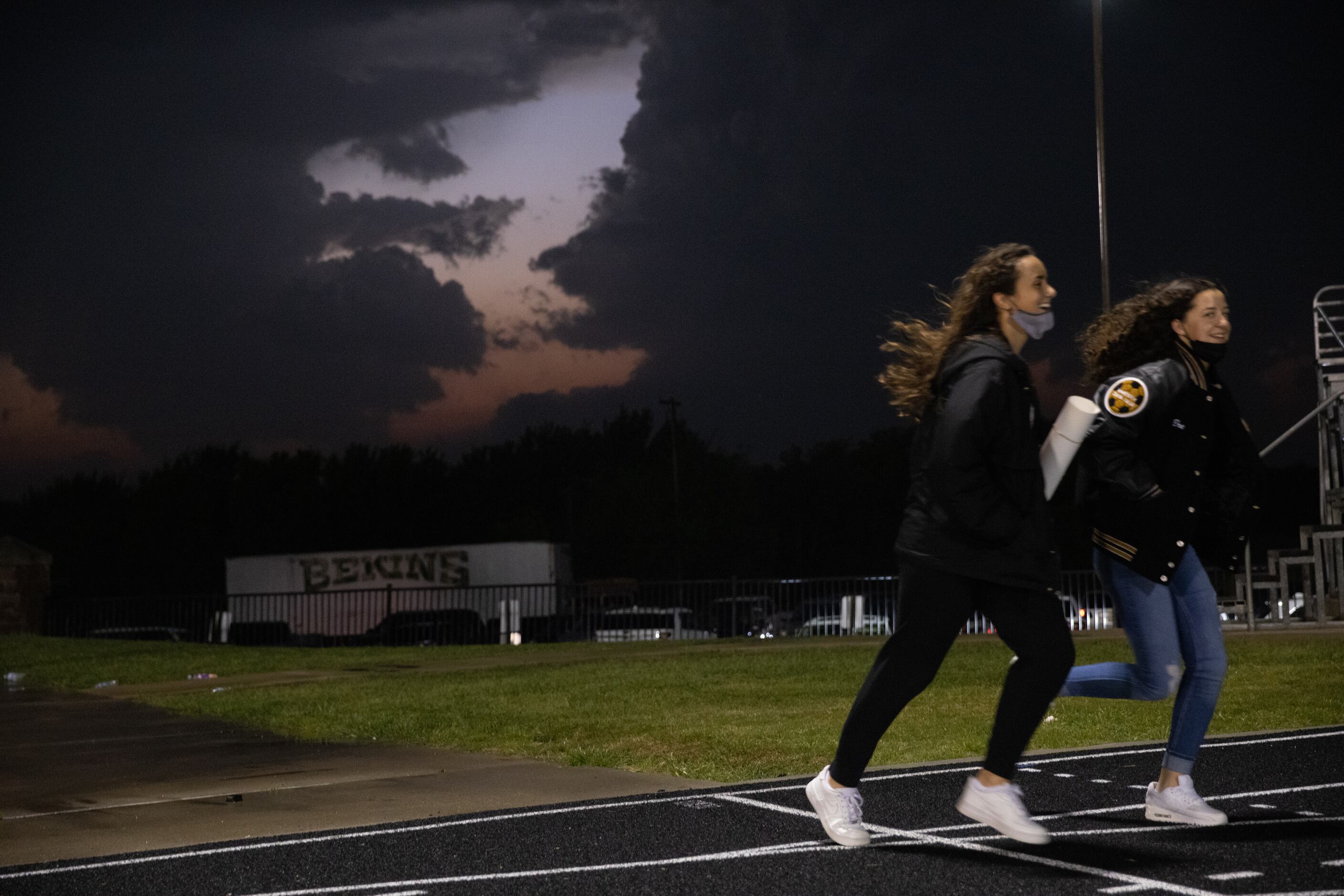 Students run across the track during the weather delay before the Celina against Palestine...