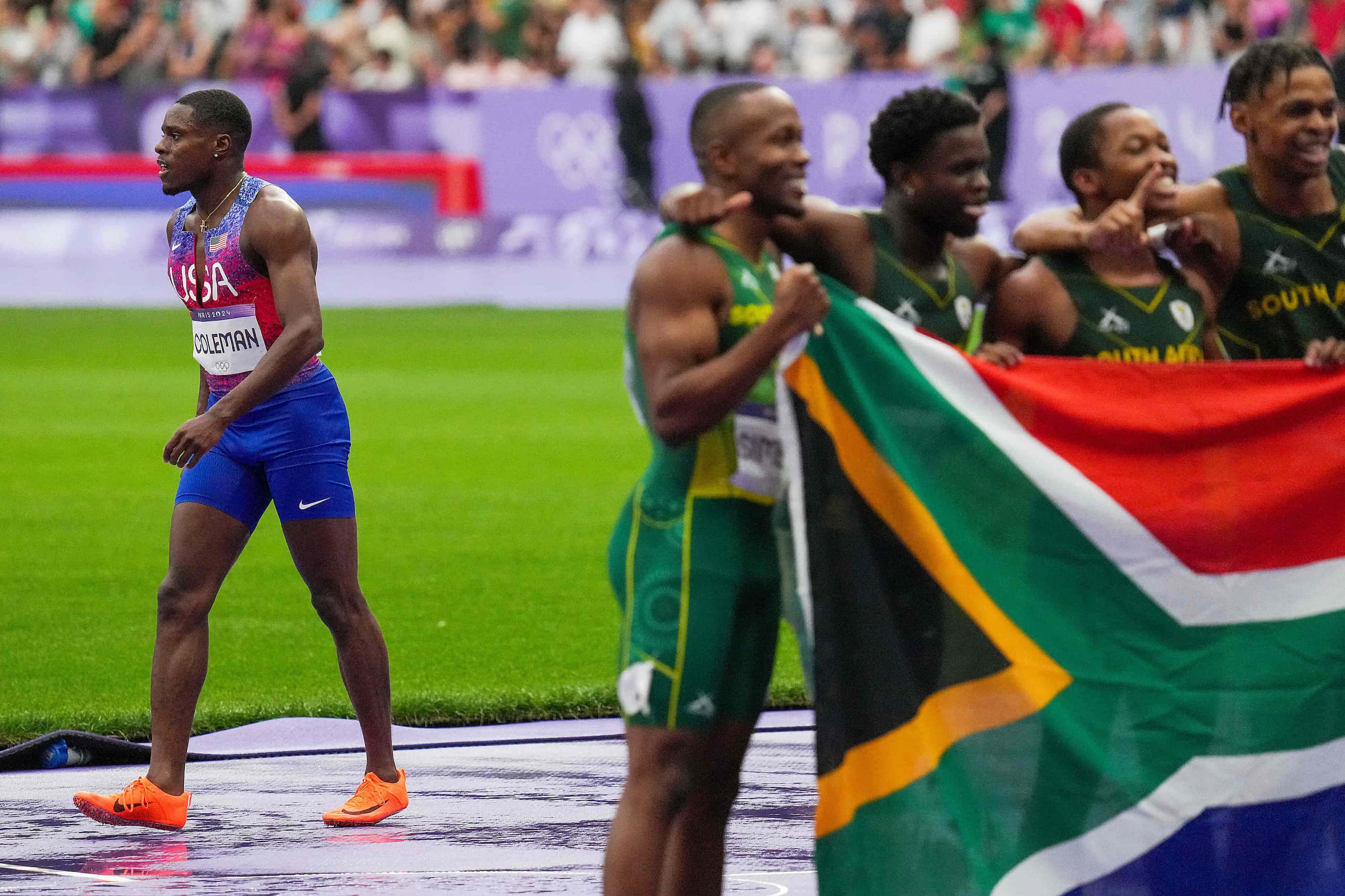 Christian Coleman of the United States walks off the track as  the team from South Africa...