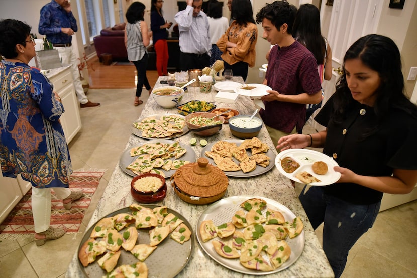 Isha Elhence, right, and Hirsh Elhence, top-right, load their plates with food during a...