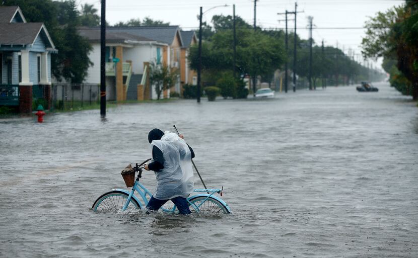 Monica Grant of Galveston pushes her bike through flooded streets near Broadway...