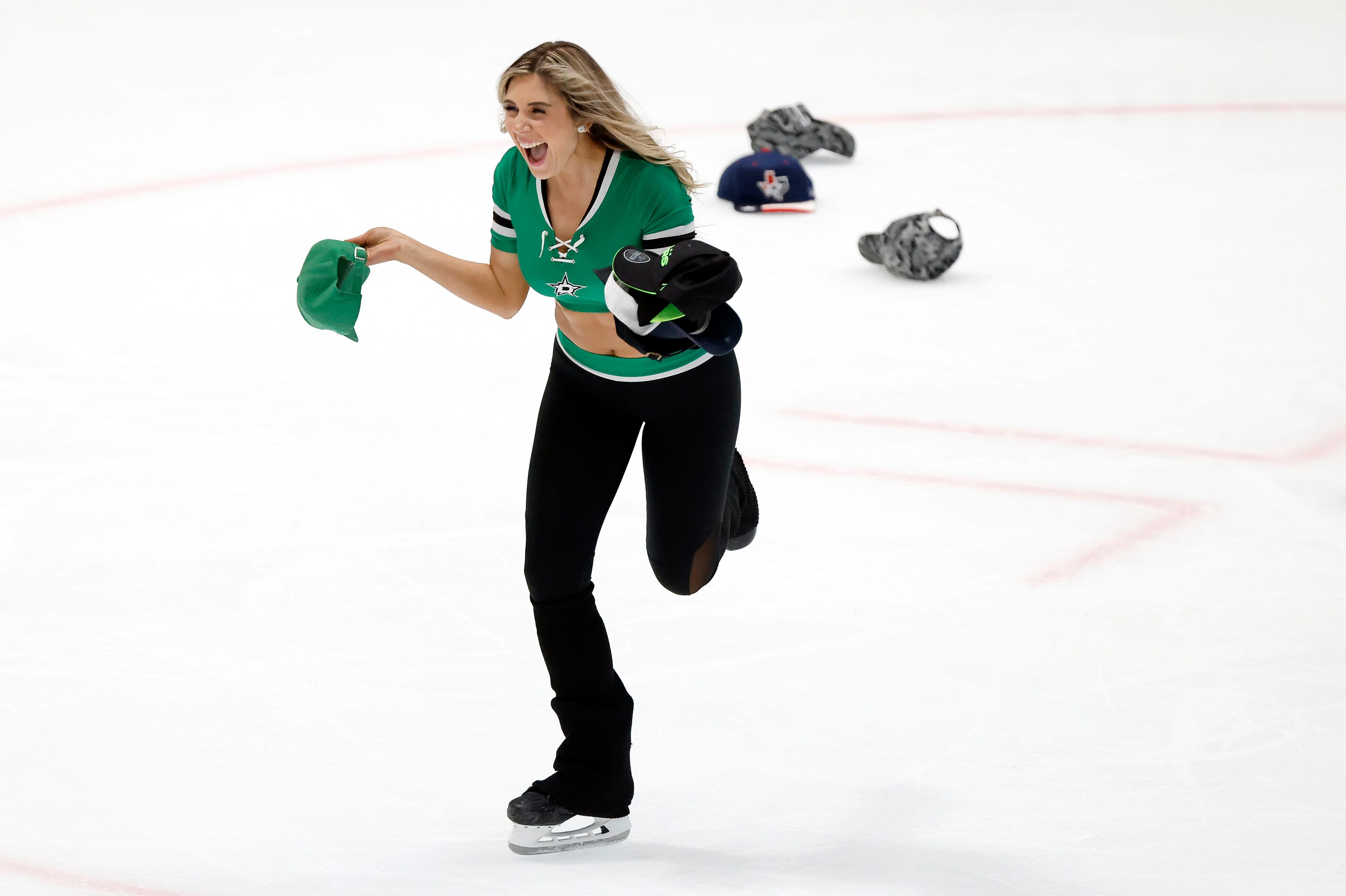 A Dallas Stars Ice Girl collects hats thrown on the ice following Dallas Stars center Joe...