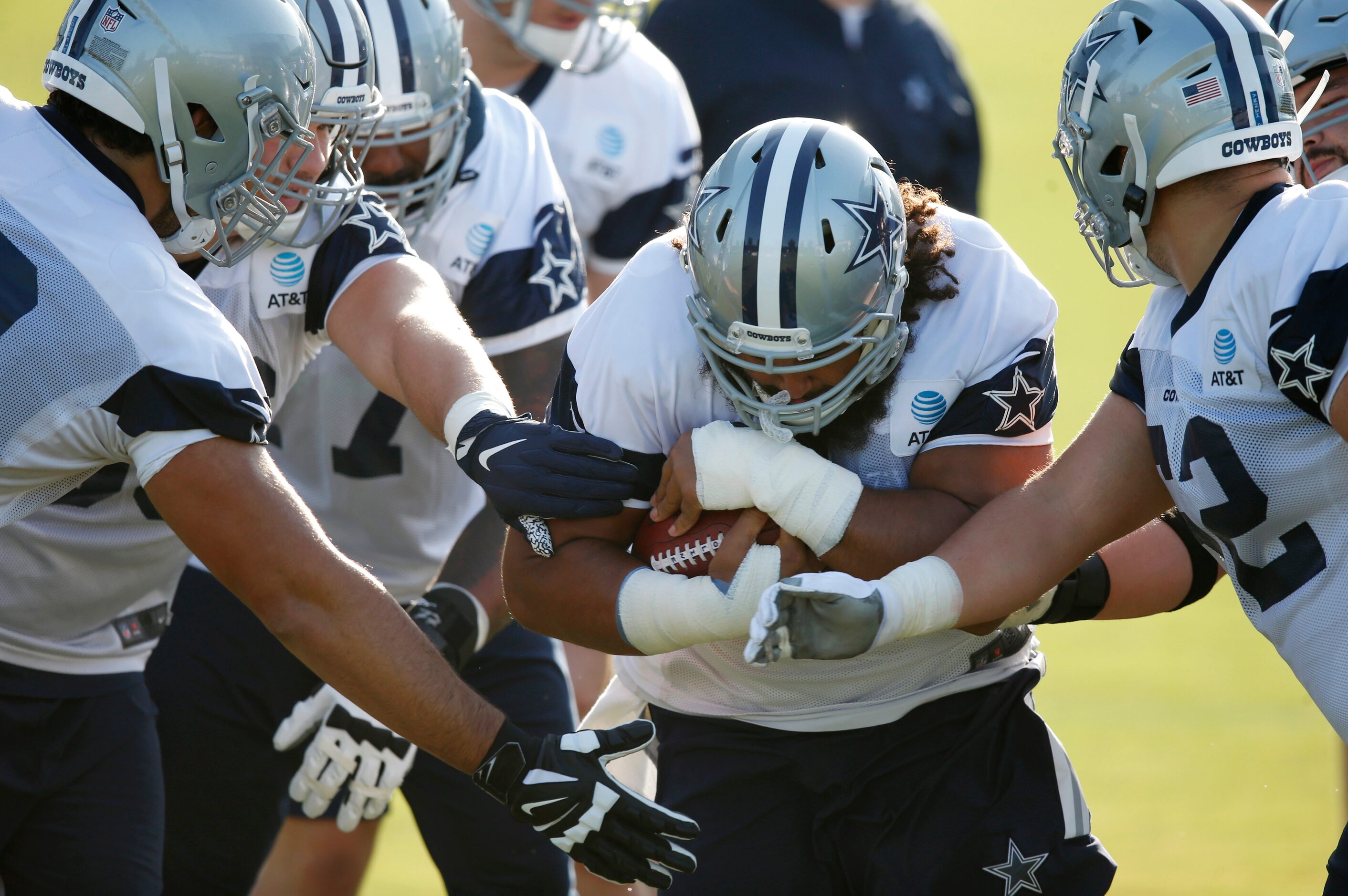 Dallas Cowboys center Joe Looney (73) holds the ball tightly as he runs through a gauntlet...