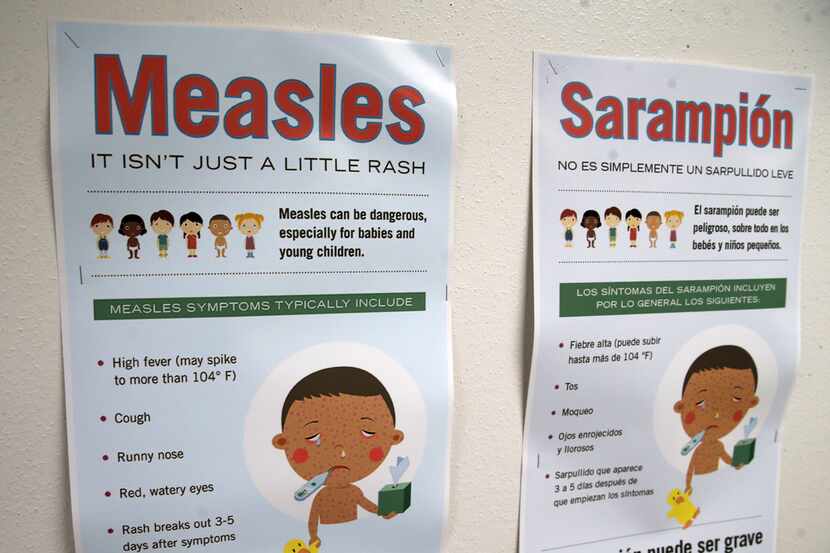Measles vaccination posters are shown in English and Spanish at the Dallas County Health &...