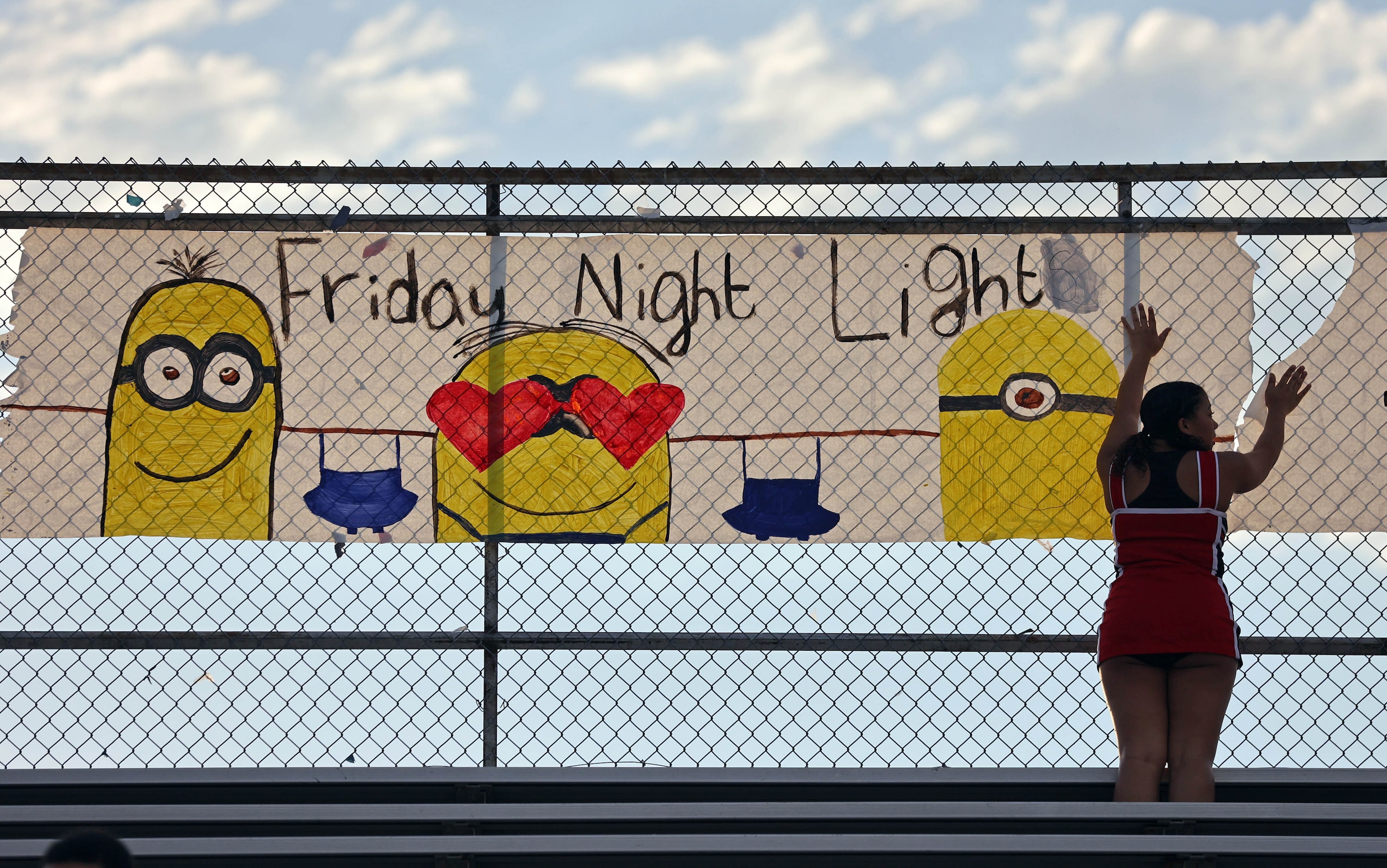 A Irving MacArthur High cheerleader puts up a minion-themed spirit banner before the start...