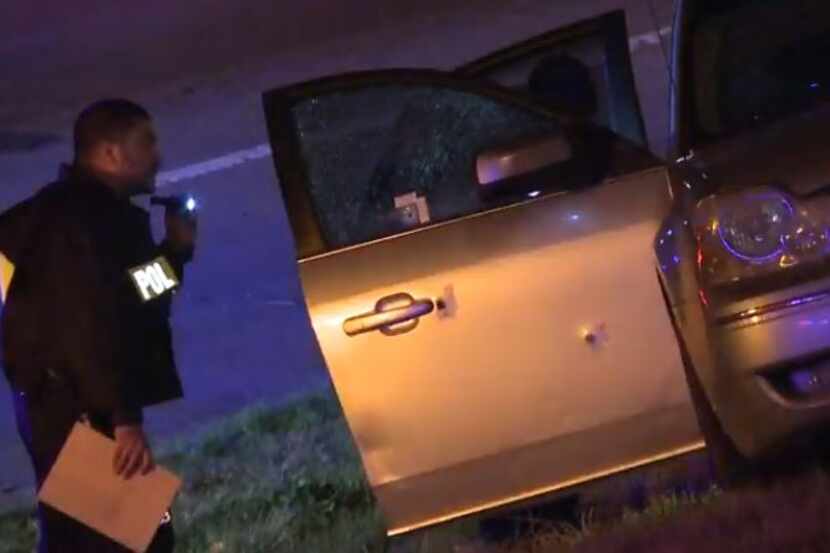Dallas police examine a car with bullet holes in it after a crash occurred Monday night near...