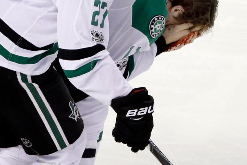 Dallas Stars left wing Curtis McKenzie (11) holds his bloody face as he is helped off the...