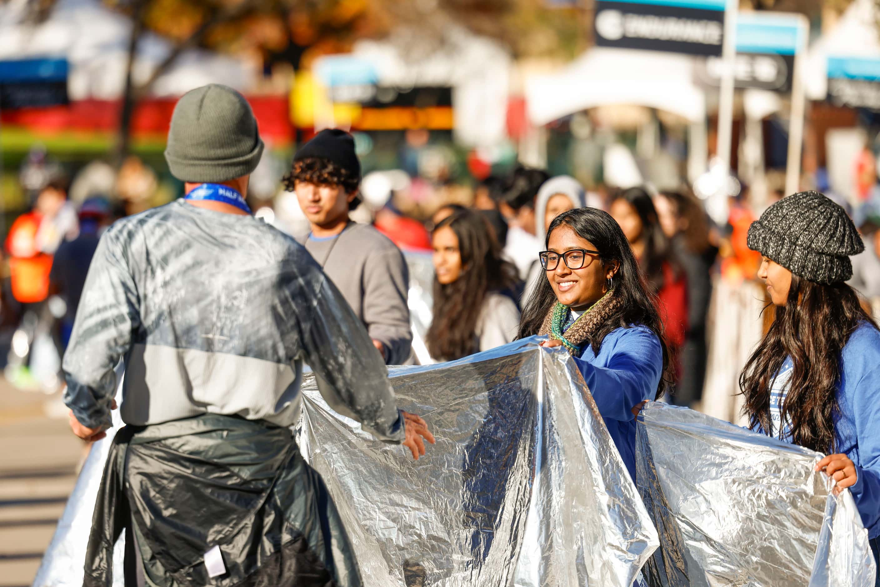 Volunteers provide heat blankets to the half marathon finishers during 2023 BMW Dallas...