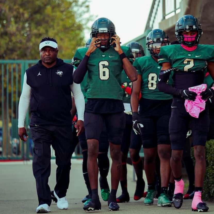 Head coach Claude Mathis (left) leads DeSoto onto the field before a game, with sons Crimson...
