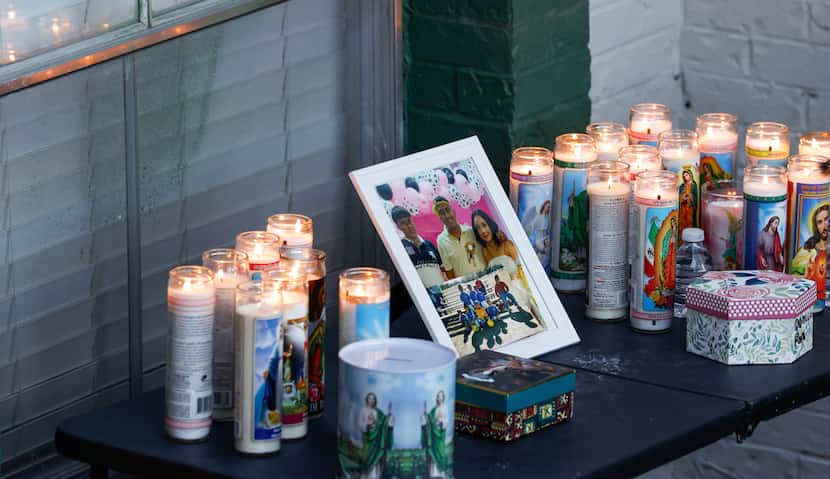 Candles burned at a vigil Tuesday outside the apartment where four people were fatally shot...