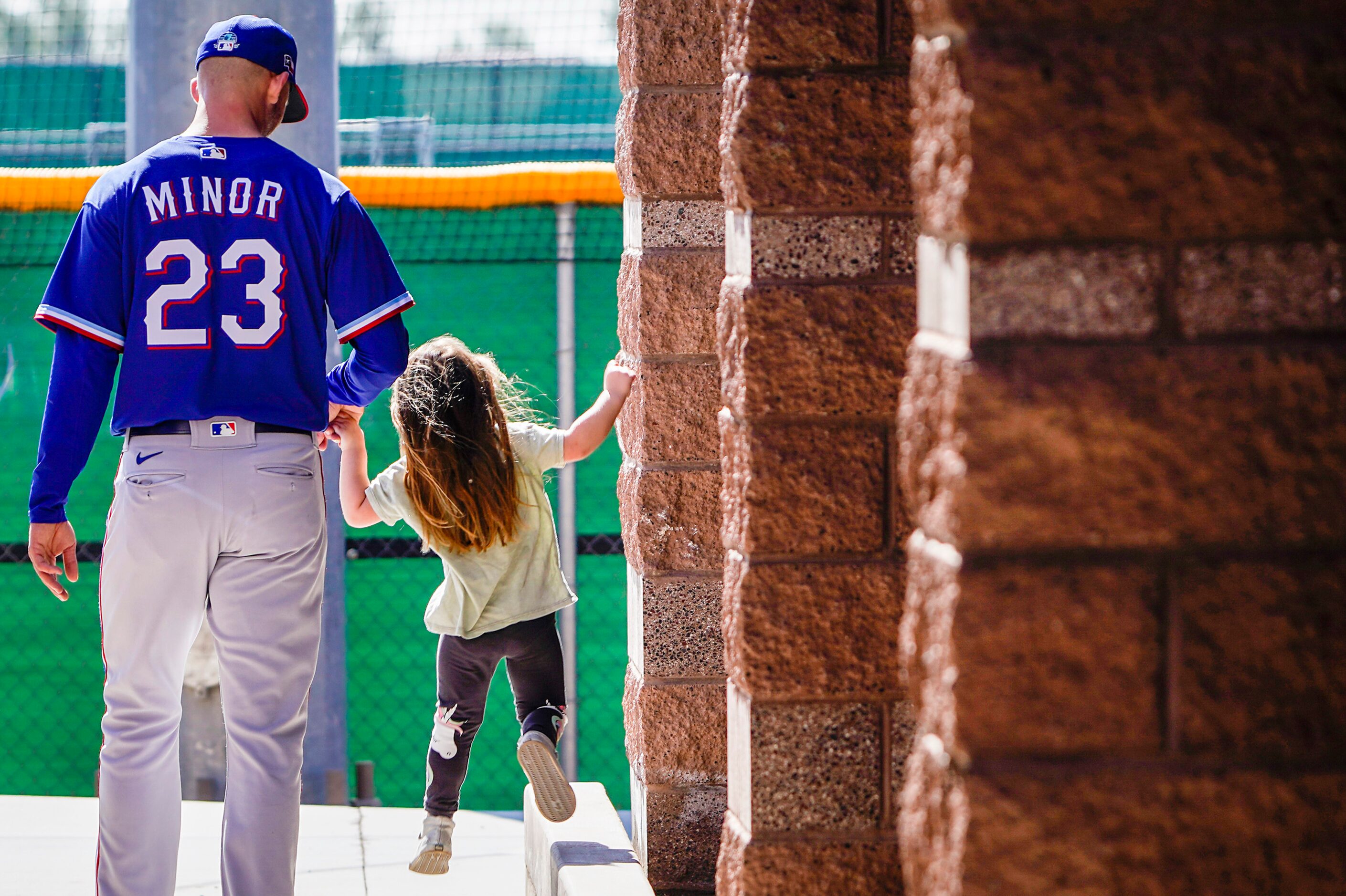 Texas Rangers pitcher Mike Minor holds hands with one of his daughters as they walk to the...