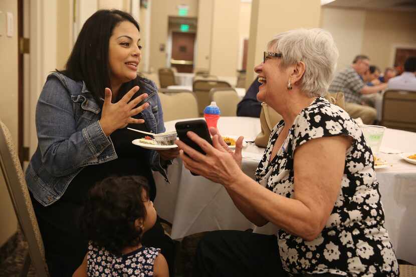 Aysha Omar (left) speaks with Nancy Stretch while feeding her daughter Dina Omar, 1, during...