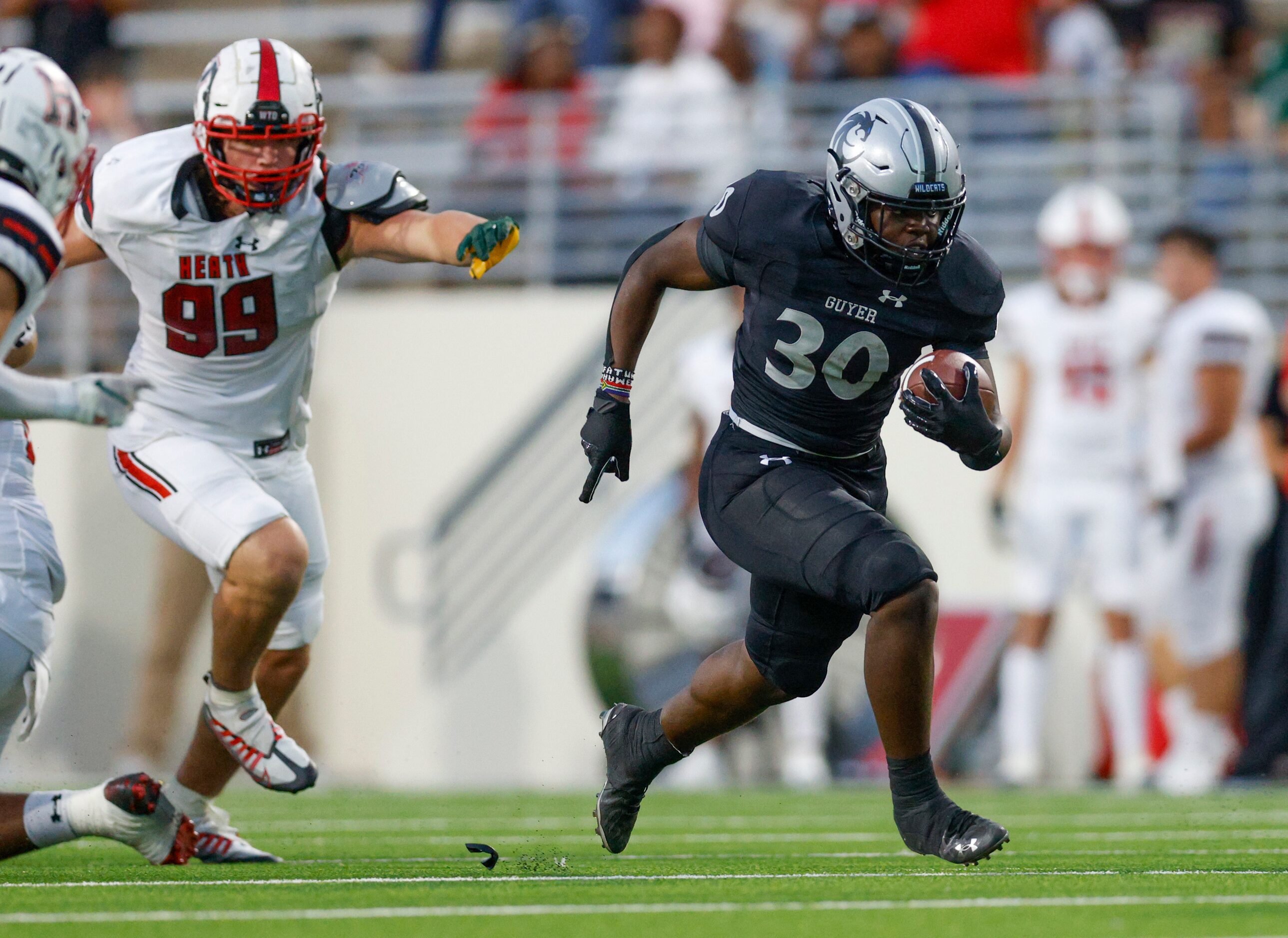 Denton Guyer running back Ahmed Yussuf (30) runs away from Rockwall-Heath defensive lineman...